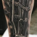 Фото татуировки на руке с изображением гитары Gibson в стиле реализм. Детализированный рисунок с использованием черных и серых оттенков.