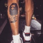 Фото тату с логотипом BAPE на ноге. Черно-белый рисунок в стиле граффити.