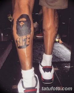 Фото тату с логотипом BAPE на ноге. Черно-белый рисунок в стиле граффити.