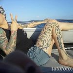 Фото тату: впечатляющий тату-рукав на ноге, выполненный в стиле трайбл с использованием черных узоров и орнаментов.