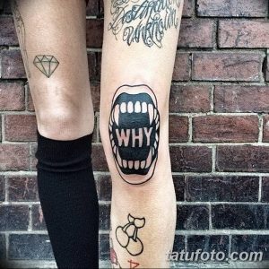 Фото тату на колене, изображающее открытый рот с зубами и надписью 'WHY'. Необычный и провокационный рисунок татуировки в стиле олдскул.