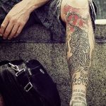 Фото тату на руке: детализированный японский дракон, обвивающий руку, и надпись 'Love and scars'. Пример сложной и красивой татуировки в стиле ориентал.