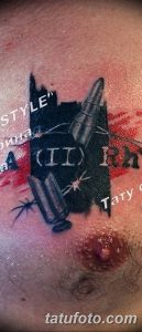 Фото тату на руке: пули, брызги краски и надписи в темном стиле. Черно-серый рисунок.