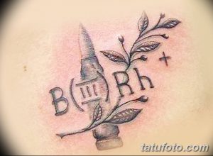 Фото тату на теле: пуля, ветка с листьями и буквы 'B Rh' в минималистичном стиле. Черно-серый рисунок.