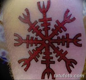 Фото тату на руке с изображением древнего рунического символа, выполненного в красном цвете. Символ имеет форму восьмиконечной звезды.