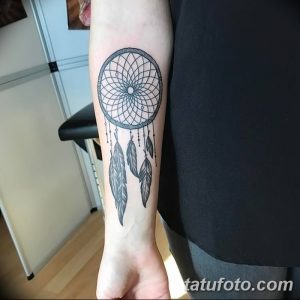 Фото тату на предплечье с изображением ловца снов, выполненное в технике blackwork с использованием тонких линий и перьев.