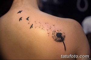 Фото минималистичной татуировки одуванчика, из которого вылетают птицы. Черно-белый рисунок татуировки на спине.