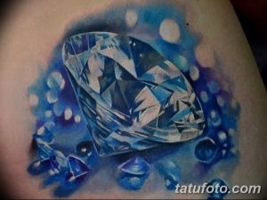 Фото тату бриллианта с каплями воды. Реалистичный рисунок татуировки, выполненный в синих и белых тонах. Идея для тату на плече.