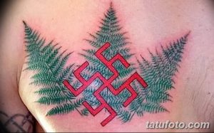 Фото татуировки на груди, изображающей красную свастику на фоне зеленых папоротников. Рисунок татуировки вызывает неоднозначные ассоциации.
