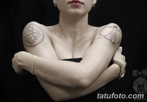Фото татуировок на плечах женщины. Слева – круг с руническими символами, справа – абстрактный геометрический рисунок.