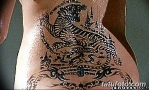 Фото тату: большая татуировка тигра в традиционном стиле с элементами тайских символов на боку.
