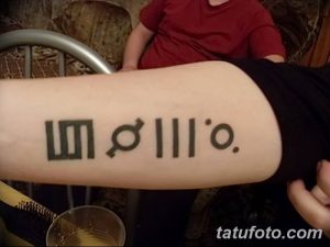 Фото тату на предплечье с минималистичным дизайном, состоящим из геометрических фигур и символов. Черно-белый рисунок, подчеркивающий простоту и лаконичность.