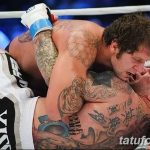 Фото татуировок на теле бойца MMA во время боя. Множество рисунков, покрывающих плечи, грудь и руки.