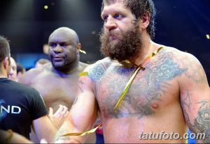 Фото тату на груди и плечах бойца MMA. Сложный рисунок в стиле традиционной татуировки с использованием черных и серых оттенков.