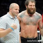 Фото тату на груди и руках бойца MMA: орнамент, религиозные символы, темные тона, реалистичный рисунок татуировки.