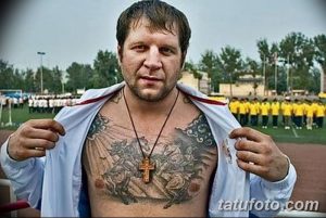 Фото тату на груди бойца MMA: крест, религиозные символы, орнамент, темные тона, реалистичный рисунок татуировки.