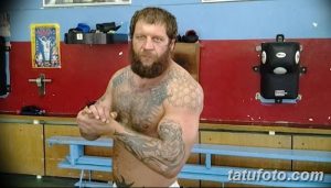 Фото тату на руке и груди бойца MMA: орнамент, темные тона, реалистичный рисунок татуировки, вид сбоку.