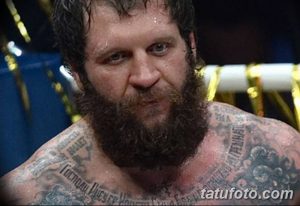 Фото тату на груди бойца MMA: крест, религиозные символы, орнамент, темные тона, реалистичный рисунок татуировки, крупный план.