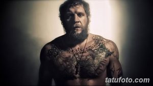 Фото тату на груди бойца MMA: крест, религиозные символы, орнамент, темные тона, реалистичный рисунок татуировки.