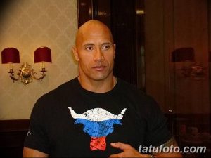 Фото тату Дуэйна Джонсона на плече с изображением головы быка. Черно-белый рисунок в минималистичном стиле.