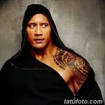 Фотография Дуэйна Джонсона в черном капюшоне, демонстрирующего татуировку на плече и груди. Мужчина смотрит в камеру.