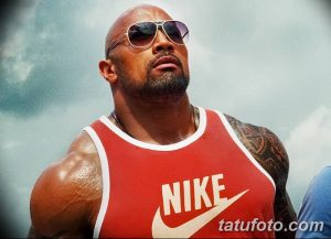 Фотография Двейна Джонсона в красной майке Nike с видимой татуировкой на плече и груди.