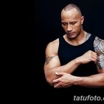 Фотография Двейна Джонсона в черной майке, демонстрирующая его татуировку в стиле полинезийских узоров на плече.