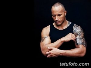 Фотография Двейна Джонсона в черной майке, демонстрирующая его татуировку в стиле полинезийских узоров на плече.