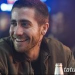 Фото тату: мужчина с татуировками на лице и шее, улыбается. Рисунок татуировки в стиле леттеринг.