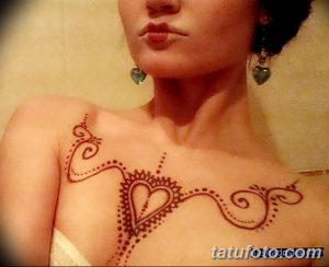 Фото тату мехенди на ключице, с изображением сердца, окруженного тонкими линиями и точками, выполненное в коричневых тонах.