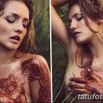 Фото тату хной на женской груди и животе, с детальным восточным орнаментом, выполненным в технике мехенди, на фоне тропической зелени.
