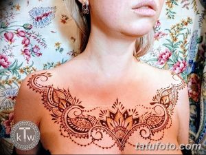 Фото тату хной на груди и плечах, выполненное в восточном стиле с использованием коричневых оттенков и цветочных мотивов.