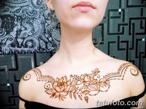 Фото тату хной на ключицах и груди, выполненное в восточном стиле с использованием коричневых оттенков и цветочных узоров.