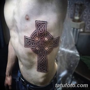 Фото тату кельтского креста на боку. Черно-серый рисунок с детально проработанными узорами.