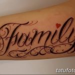 Фото татуировки с надписью 'Family' выполненной красивым шрифтом и украшенной маленьким красным сердцем. Расположена на предплечье.