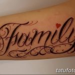 Фото татуировки с надписью 'Family' выполненной красивым шрифтом и украшенной маленьким красным сердцем. Расположена на предплечье.