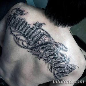 Фото тату надписи 'Family Forever' на спине, выполненной в черном цвете с декоративными элементами и растительным орнаментом. Масштабный рисунок татуировки для мужчин.