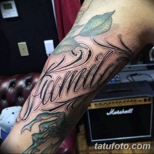 Фото тату надписи 'Family' на предплечье, выполненной в черном цвете с декоративными элементами и растительным орнаментом. Идеальный эскиз тату для семьи.