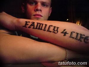 Фото тату надпись 'FAMILY 4 LIFE' на предплечье мужчины. Черный цвет, готический шрифт, прямолинейный стиль.
