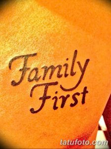 Фото тату надпись 'Family First' на загорелой коже. Использованы теплые коричневые тона, шрифт стилизован под рукописный.