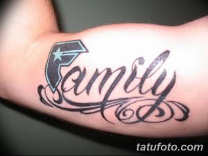 Фото татуировки на запястье с надписью 'Family', стилизованной под логотип и украшенной декоративными элементами. Черно-голубой рисунок.