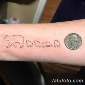 Фото тату с изображением семьи медвежат на руке, выполненной в минималистичном стиле тонкими линиями.