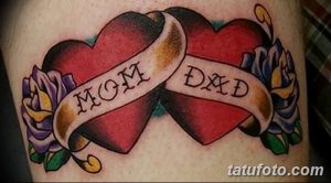 Фото татуировки двух сердец с надписями 'Mom' и 'Dad' на лентах, украшенных цветами. Цветной рисунок татуировки.