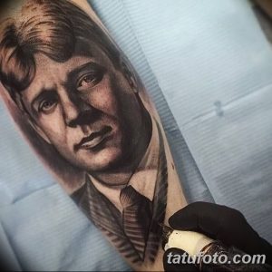 Крупный план черно-белой татуировки с гиперреалистичным портретом мужчины на руке. Детализированная проработка лица, волос и одежды создает эффект присутствия.
