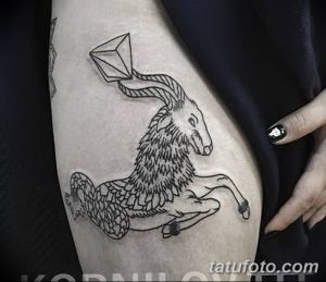 Черно-белое фото тату на бедре с изображением козла с рогами в форме бриллианта. Сюрреалистичный и символический стиль.