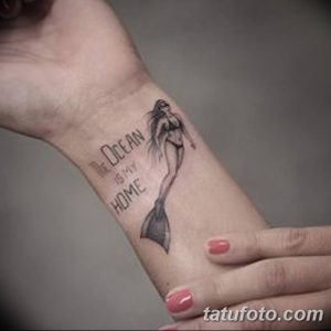 Фото тату русалки на запястье. Небольшой рисунок с изображением девушки с рыбьим хвостом и надписью "The Ocean is my Home". Черно-белое исполнение.