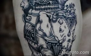 Фото тату слона с всадником на руке. Черно-белый рисунок татуировки в стиле графика с высокой детализацией и экзотическим сюжетом.