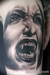 Фото тату кричащей вампирши на руке. Черно-белый рисунок татуировки с открытым ртом и острыми клыками, выполненный в реалистичном стиле.
