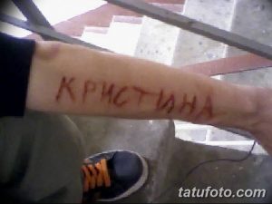 Фото тату с именем 'Kristina', выполненным красными чернилами на руке. Простой, рукописный стиль.
