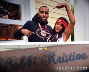 Фото татуировки с надписью "Bobbi Kristina", выполненной каллиграфическим шрифтом, на предплечье руки мужчины. На фото также изображена девушка.